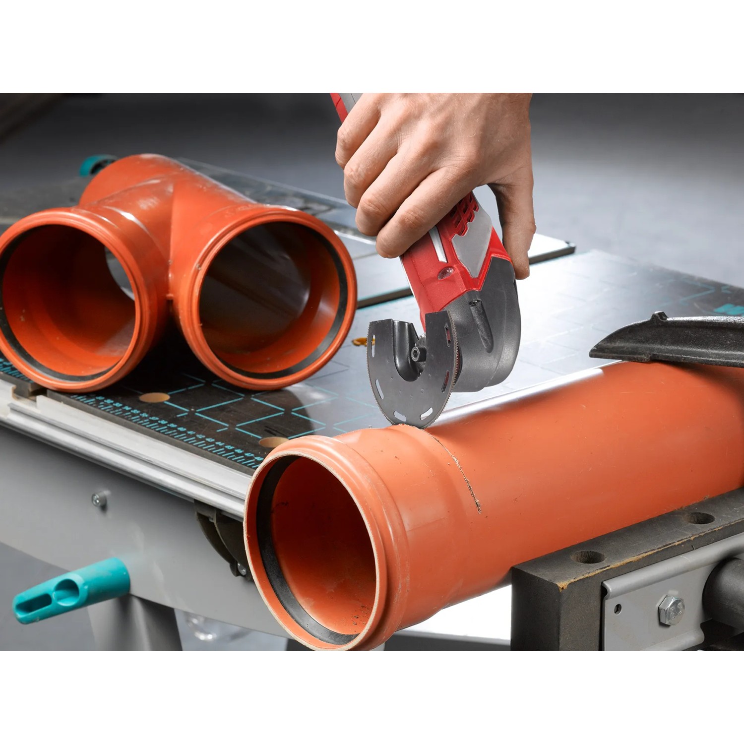 Einhell Multitool im Einsatz: Schneiden eines orangefarbenen Kunststoffrohrs. Zubehör für Multifunktionswerkzeuge.