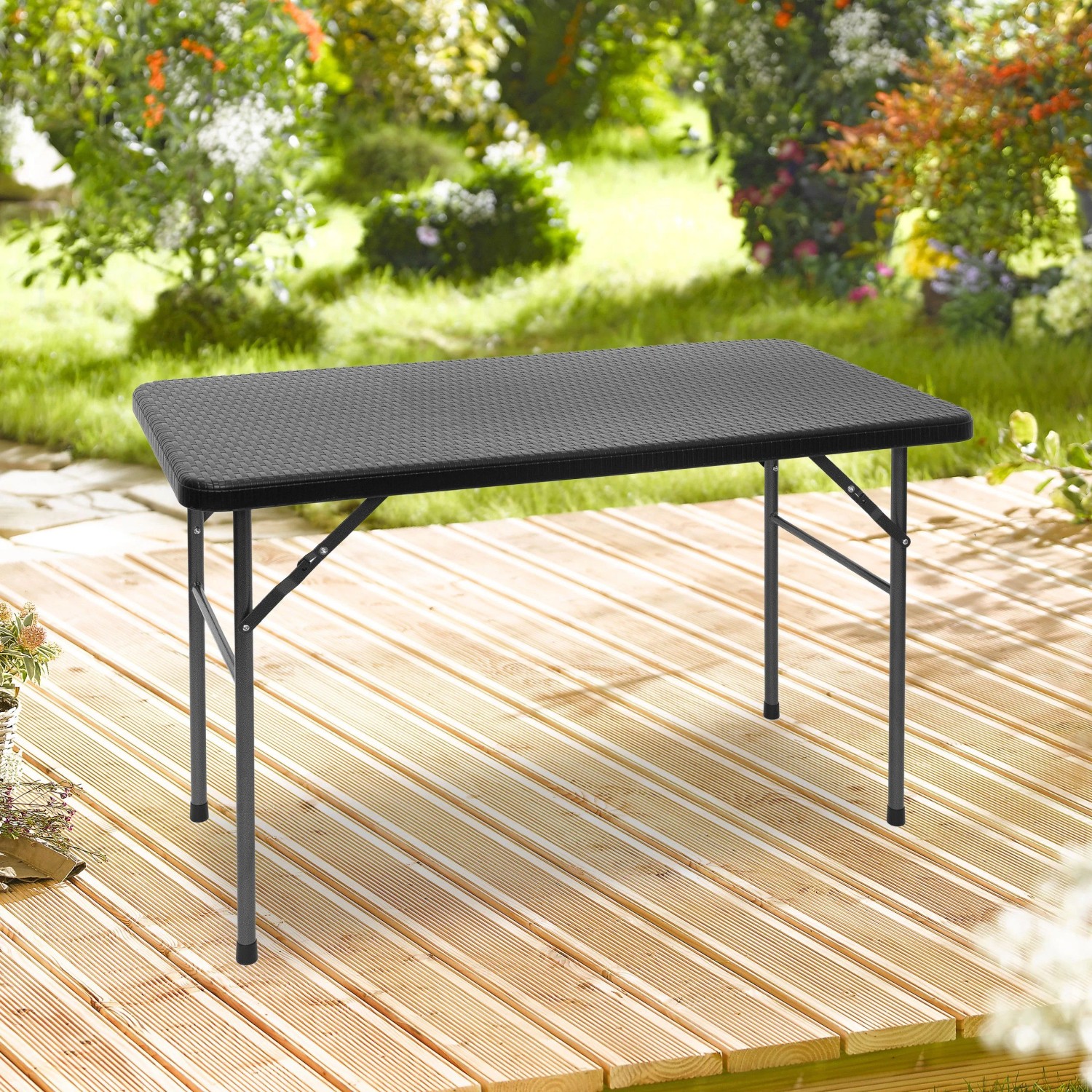 Schwarzer rechteckiger Relaxdays Klapp-Gartentisch aus Kunststoff in Rattan-Optik auf einer Holzterrasse im Garten.