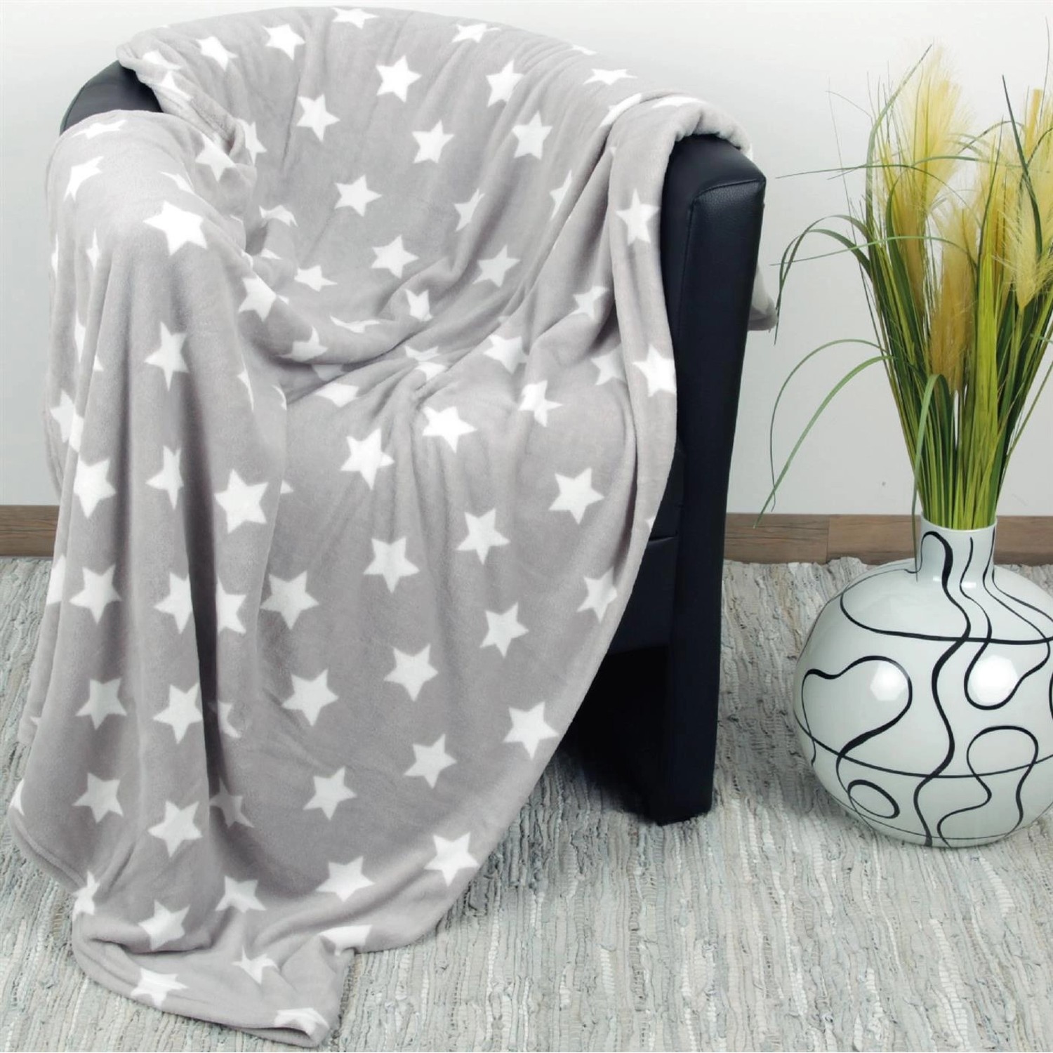 Hellgraue Bestlivings Kuscheldecke mit Sternenmuster auf einem Sessel. Ideal als Sofa- oder Bettüberwurf.