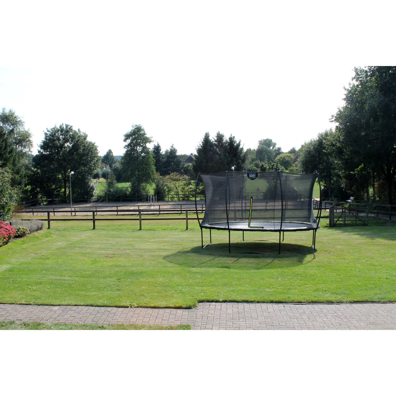 Grünes EXIT Silhouette Trampolin D305cm mit Sicherheitsnetz im Garten.