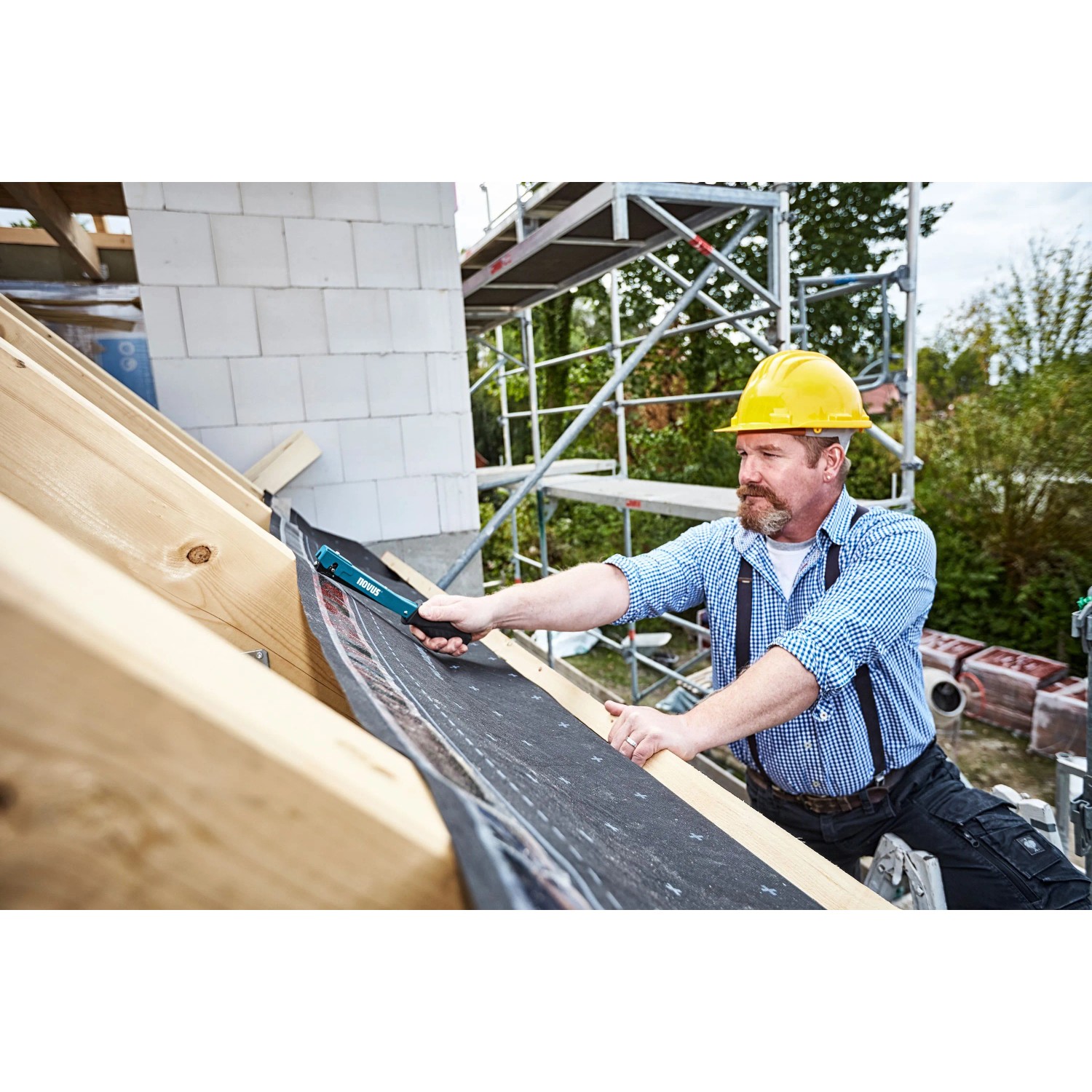 Handwerker befestigt Bitumenschindeln mit Novus Hammertacker J-022 auf einem Dach.