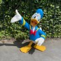 Gartenfigur Donald Duck, blaue Jacke, rote Fliege, gelbe Füße, winkend.