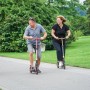 Familie fährt mit Six Degrees Aluminium Scooter (rot) auf einem Weg im Park.