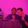 Zwei Männer spielen ein Basketball Trinkspiel aus transparentem Kunststoff mit Schnapsgläsern bei Partybeleuchtung.