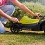 Ryobi Akku-Rasenmäher RLM18X33B40 in Aktion, gelb/schwarz, mit Bediener im Garten.