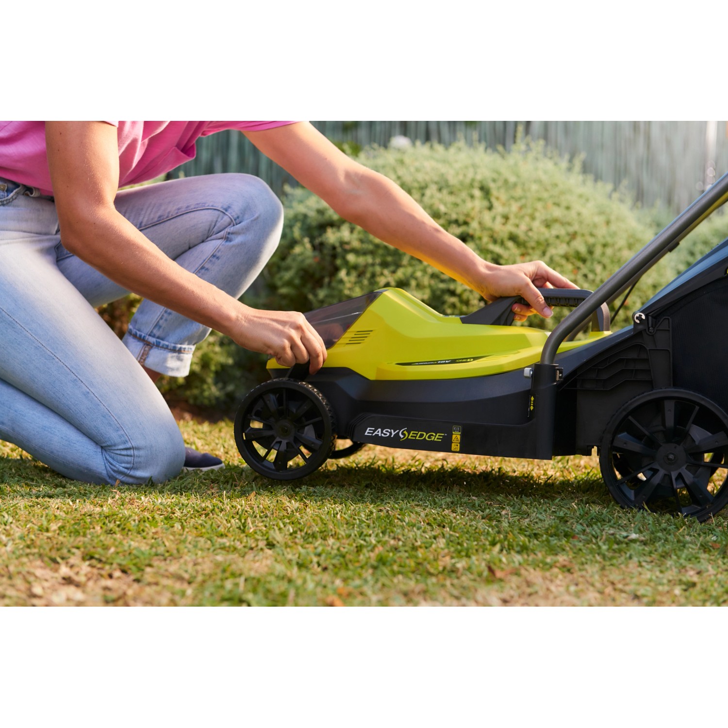 Ryobi Akku-Rasenmäher RLM18X33B40 in Aktion, gelb/schwarz, mit Bediener im Garten.