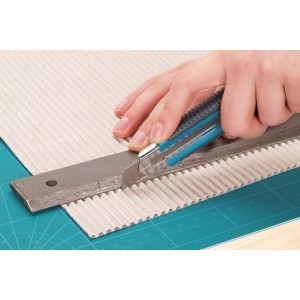 Wolfcraft Abbrechklingen-Messer 18 mm schneidet Pappe mit Metall-Lineal auf Schneideunterlage.