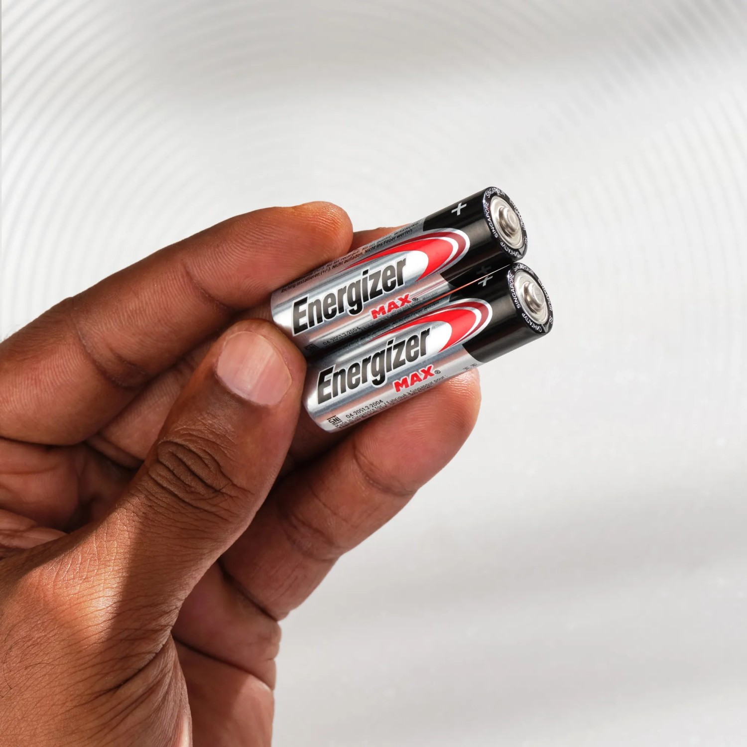 Hand hält zwei Energizer Max AA Batterien. Alkaline Batterien für Geräte des täglichen Gebrauchs.