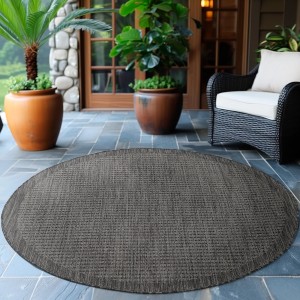 Schwarzer, runder Ayyildiz Outdoor-Teppich Giza (200x200 cm) in Sisal-Optik auf einer Terrasse.