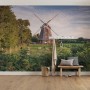 Vlies Fototapete „Tage wie Diese“ mit Windmühle, Landschaft und Bank im Raum.