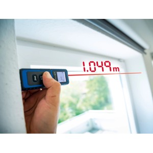 LUX-TOOLS Laserentfernungsmesser im Einsatz, Messwerkzeug mit rotem Laserstrahl am Fenster.