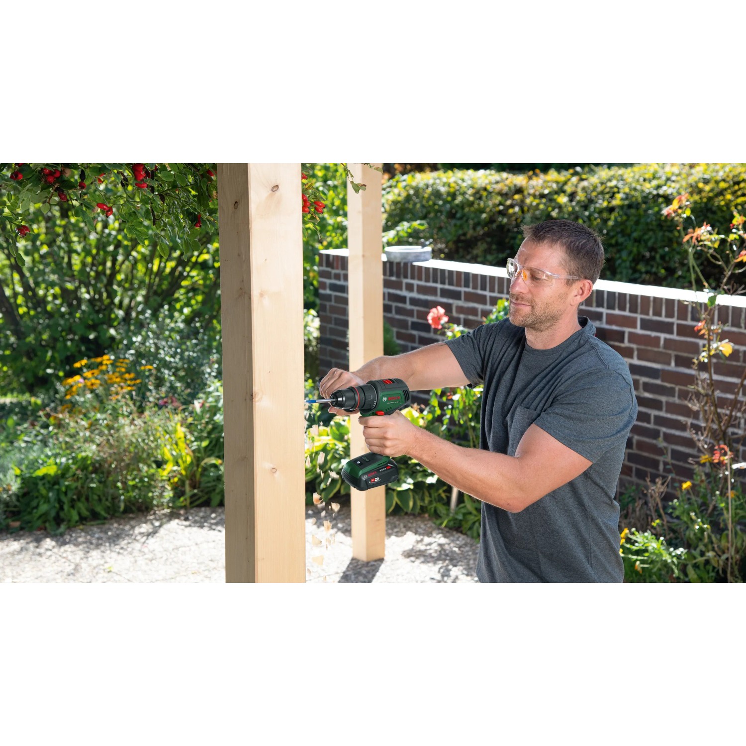 Mann schraubt mit Bosch Akku-Bohrschrauber AdvancedDrill 18V-80 ein Brett im Garten.