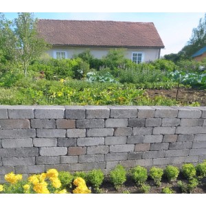 Mauer aus EHL Verona Antik Light Mauersteinen in Muschelkalk mit Garten im Hintergrund.