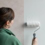 Frau tapeziert Vliestapete mit Farbroller. Wallpro Tapezierwerkzeug im Einsatz.