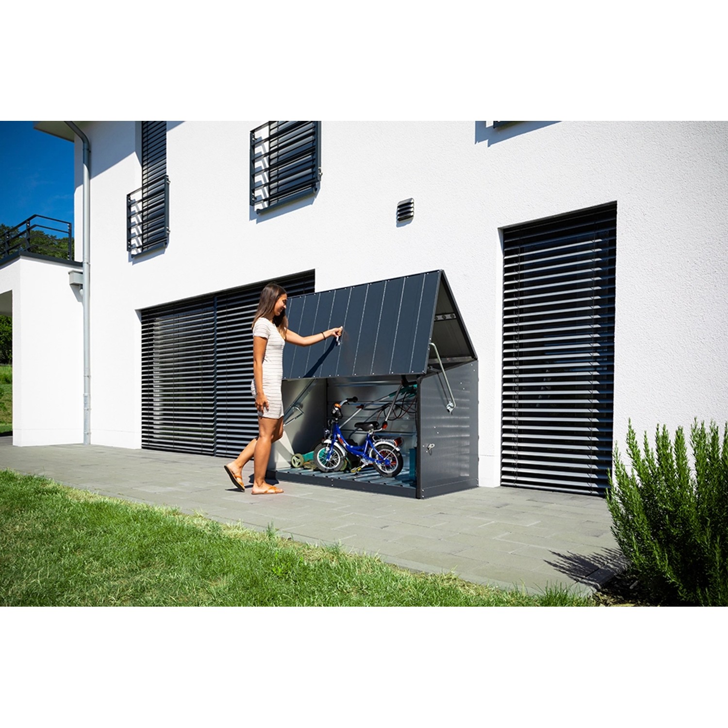 Trimetals Aufbewahrungsbox Storeguard Anthrazit mit Fahrrädern vor weißer Hauswand.