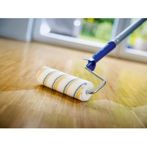Lackwalze von LUX PRO (blau-gelb, 18 cm) beim Lackieren eines Holzbodens.