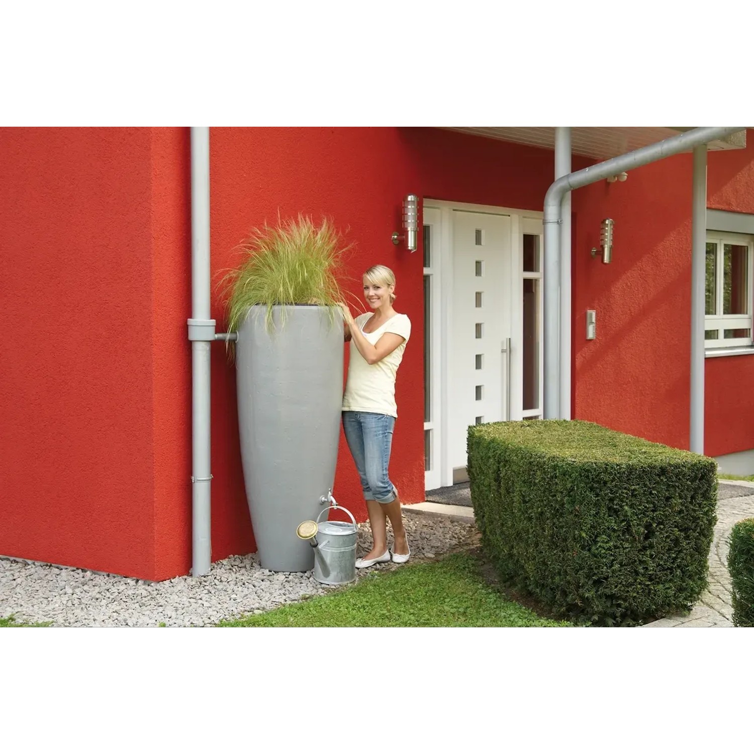 Garantia 2in1 Wasserbehälter in Zinkgrau mit Pflanzschale und Frau im Garten.