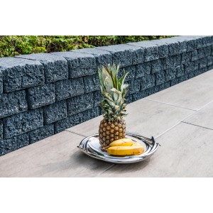 Diephaus Mauerstein Munin Basalt, graue Mauer mit Ananas und Bananen auf einem Tablett.