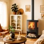 Schwarzer Panadero Baikal Kaminofen (6,7 kW) im Wohnraum mit Holzscheiten unter dem Brennraum.