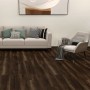 Verlegter, dunkler Click-Vinylboden Felizitas Eiche im Wohnraum mit Sofa und Sessel.