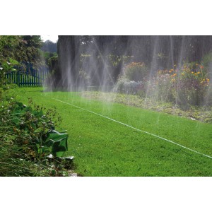 Gardena Schlauch-Regner 7,5 m bewässert Rasenfläche mit feinem Sprühregen im Garten.