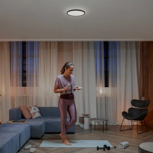 Philips Hue Tento LED-Panel, Ø 29,1 cm, in Schwarz an der Decke eines Wohnzimmers.