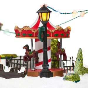 Weihnachtsdorf Szene mit beleuchteter Laterne, rotem Karussell und Schnee. Festliche Kunststoff-Dekoration.
