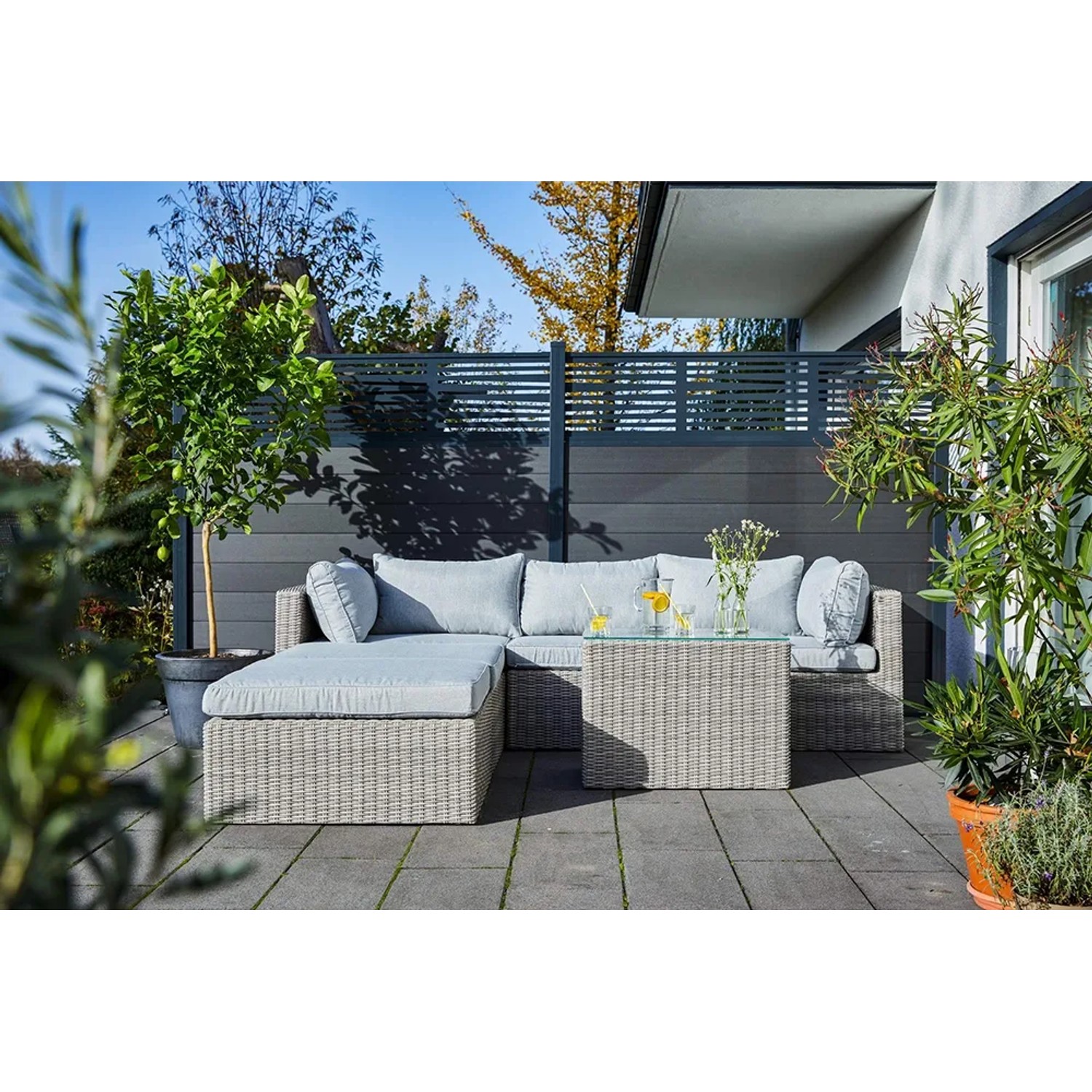 Lounge-Gartenmöbel: Sandfarbene Polyrattan Lounge-Sessel Olea mit hellgrauen Kissen auf Terrasse.