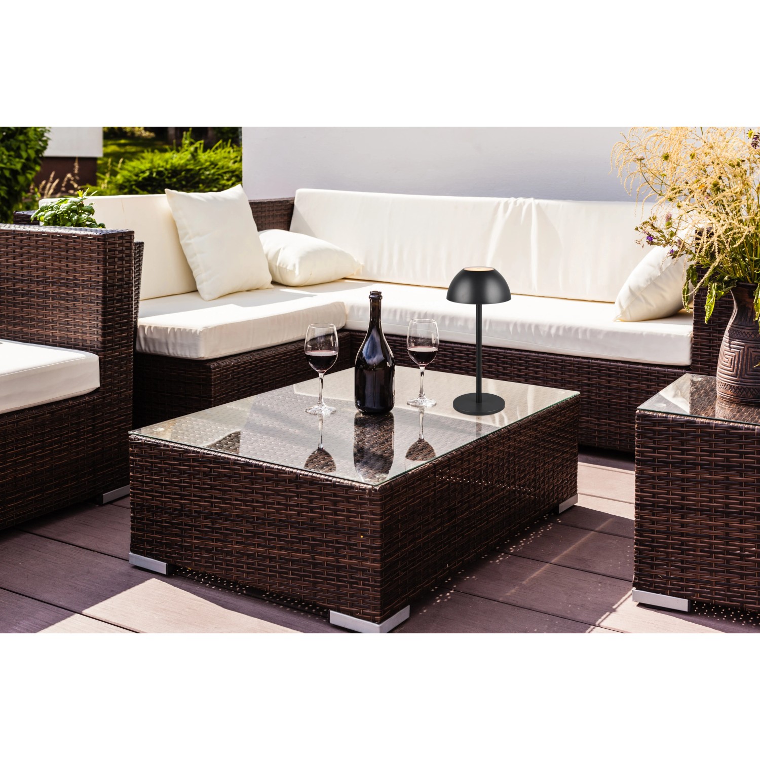 Schwarze Reality LED-Tischleuchte Ricardo auf Gartentisch mit Deko.