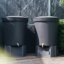 Zwei graue Regentonnen mit Messing-Anschluss-Set im Garten.