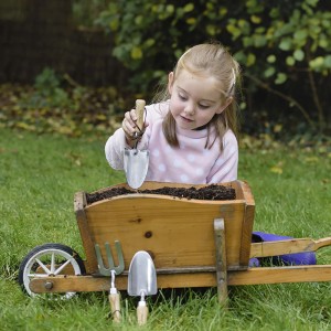 Mädchen mit Kent & Stowe Kinder-Handschaufel (20 cm) und Schubkarre im Garten.