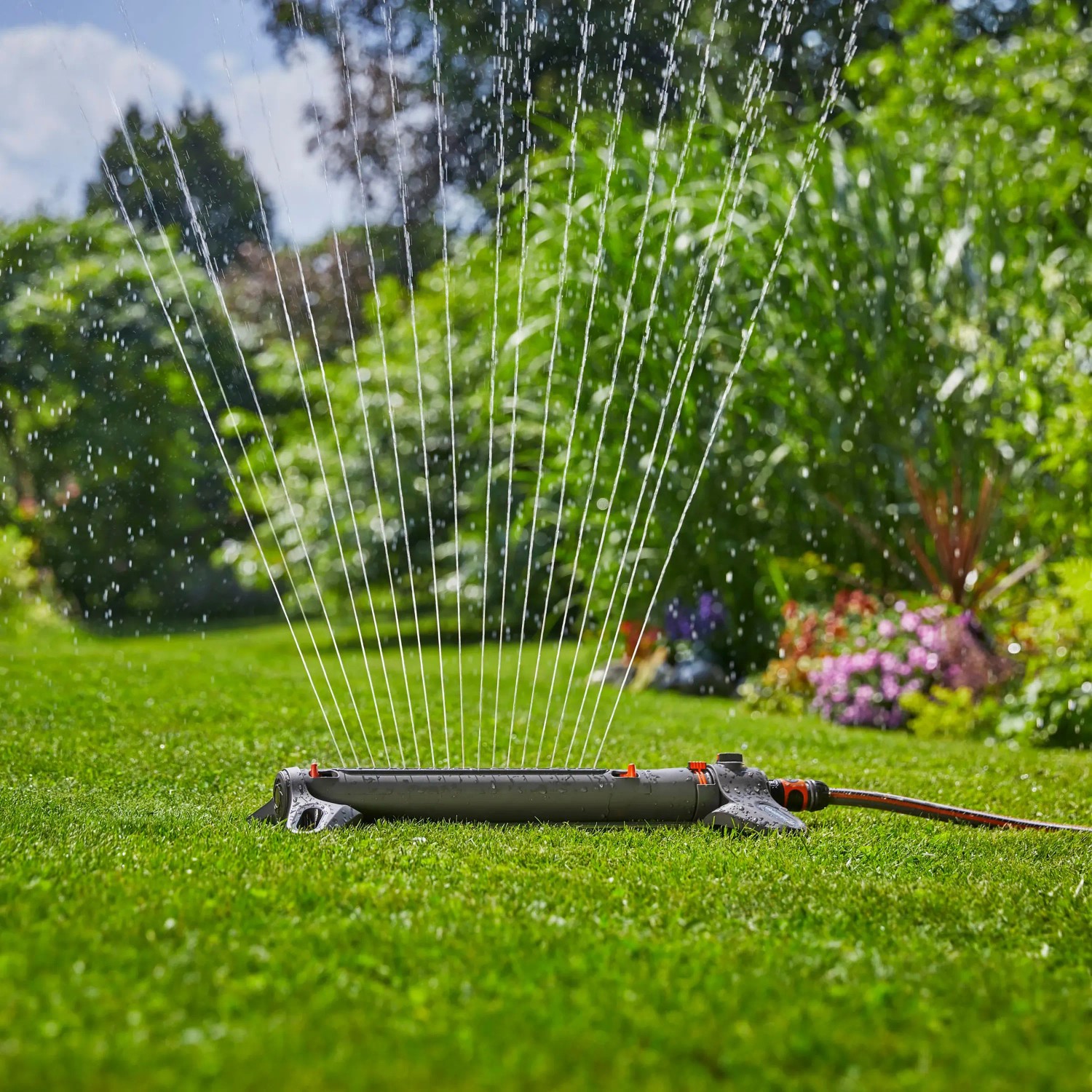 Gardena AquaZoom L Viereckregner bewässert Rasenfläche. Sprinkler im Einsatz auf Grünfläche.