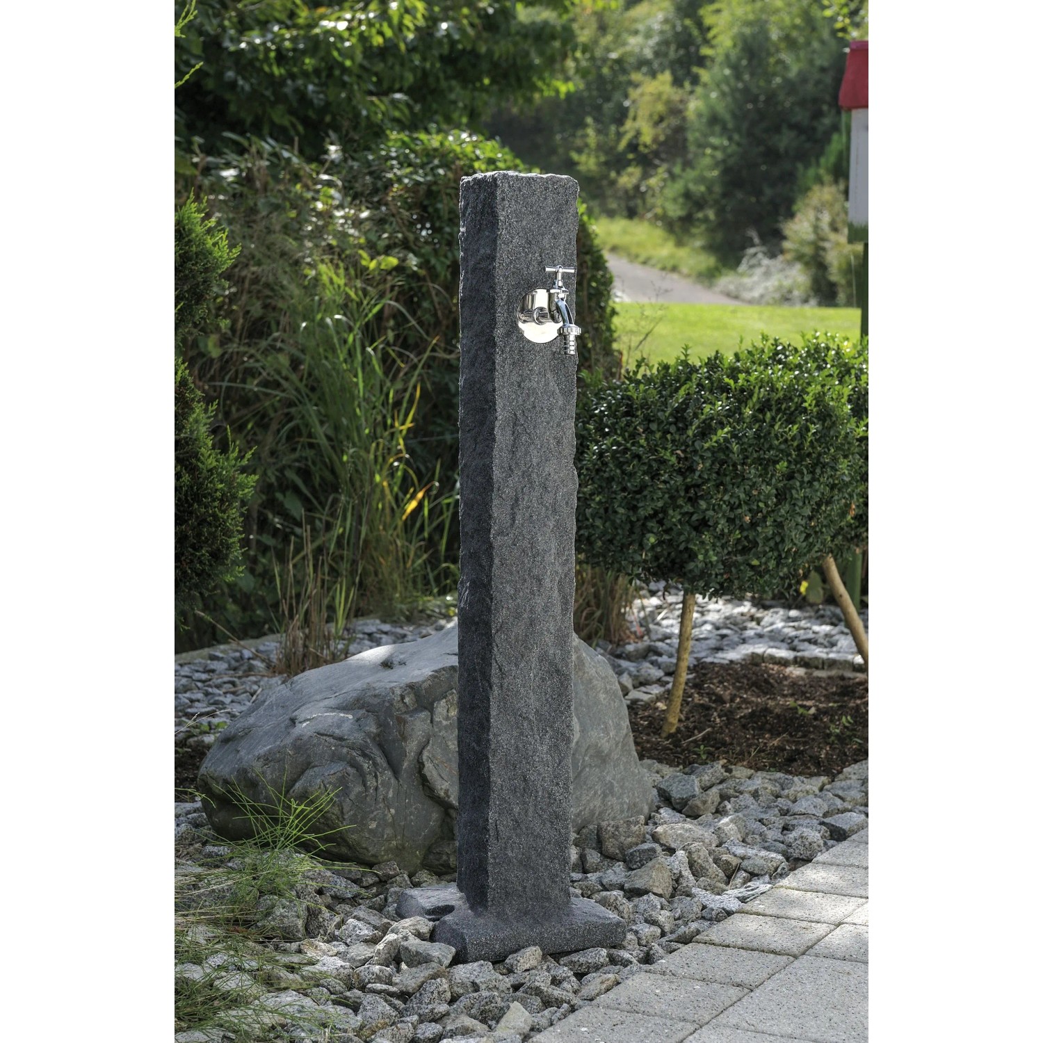 Arves Wasserzapfstelle Natura Black Granit im Garten mit Chromhahn.