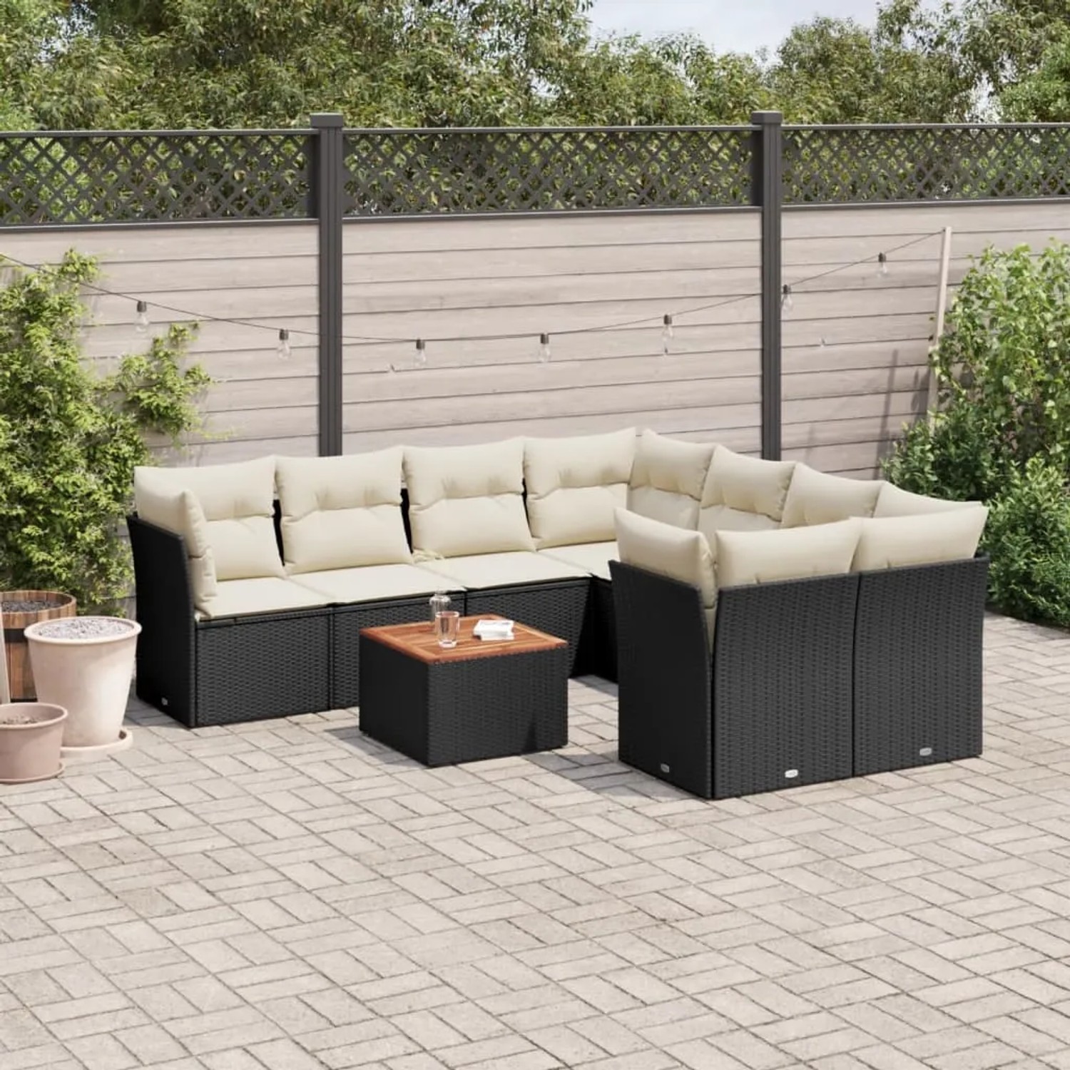 Schwarze 9-tlg. Garten-Sofagarnitur aus Poly Rattan mit cremefarbenen Kissen und Tisch.