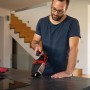 Mann reinigt mit rotem Einhell Akku-Handstaubsauger Krümel von dunkler Küchenarbeitsplatte.