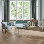 Wohnraum mit Parador Laminat Trendtime 3 Eiche Skyline Fischgrät Grau im Fischgrätmuster verlegt.