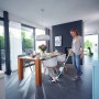 Frau nutzt Leifheit Akku-Saugwischer Regulus Aqua PowerVac zur Bodenreinigung im Esszimmer.