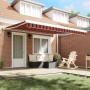 vidaXL Einziehbare Markise mit rot-schwarzen Streifen über einer Terrasse am Ziegelhaus.