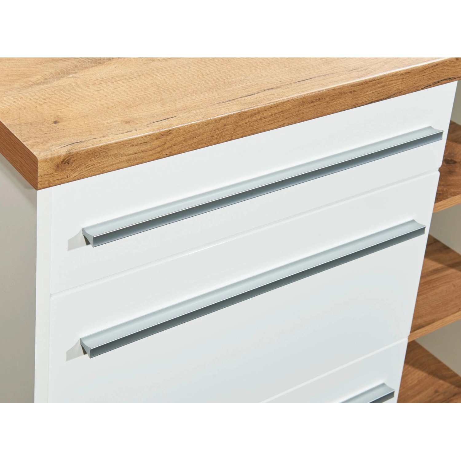 Detailansicht: Weiße Respekta Küchenzeile mit Kücheninsel und Schubladen mit silbernen Griffen.