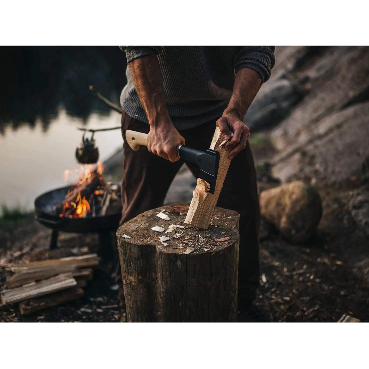 Mann spaltet Holz mit der Fiskars Universalaxt Norden N10 am Lagerfeuer.