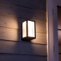 Schwarze Philips Hue LED-Wandleuchte Impress mit warmweißem Licht an Hauswand.