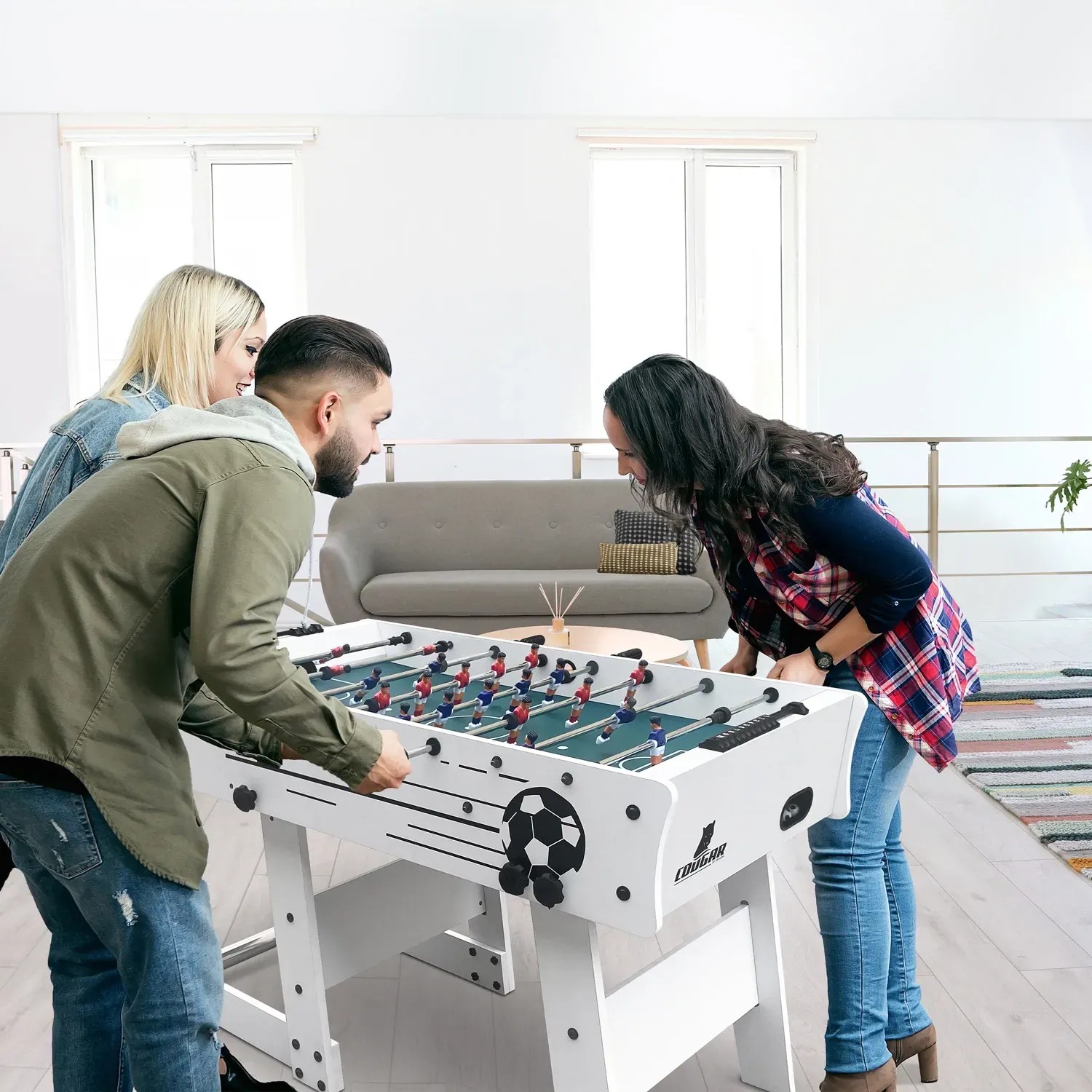 Weißer Cougar Tischkicker Scorpion Kick TS (faltbar) mit spielenden Personen im Wohnraum.