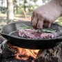Petromax Grillpfanne Gusseisen 35cm mit Steak auf offenem Feuer. Grillutensil für Outdoor-Küche.