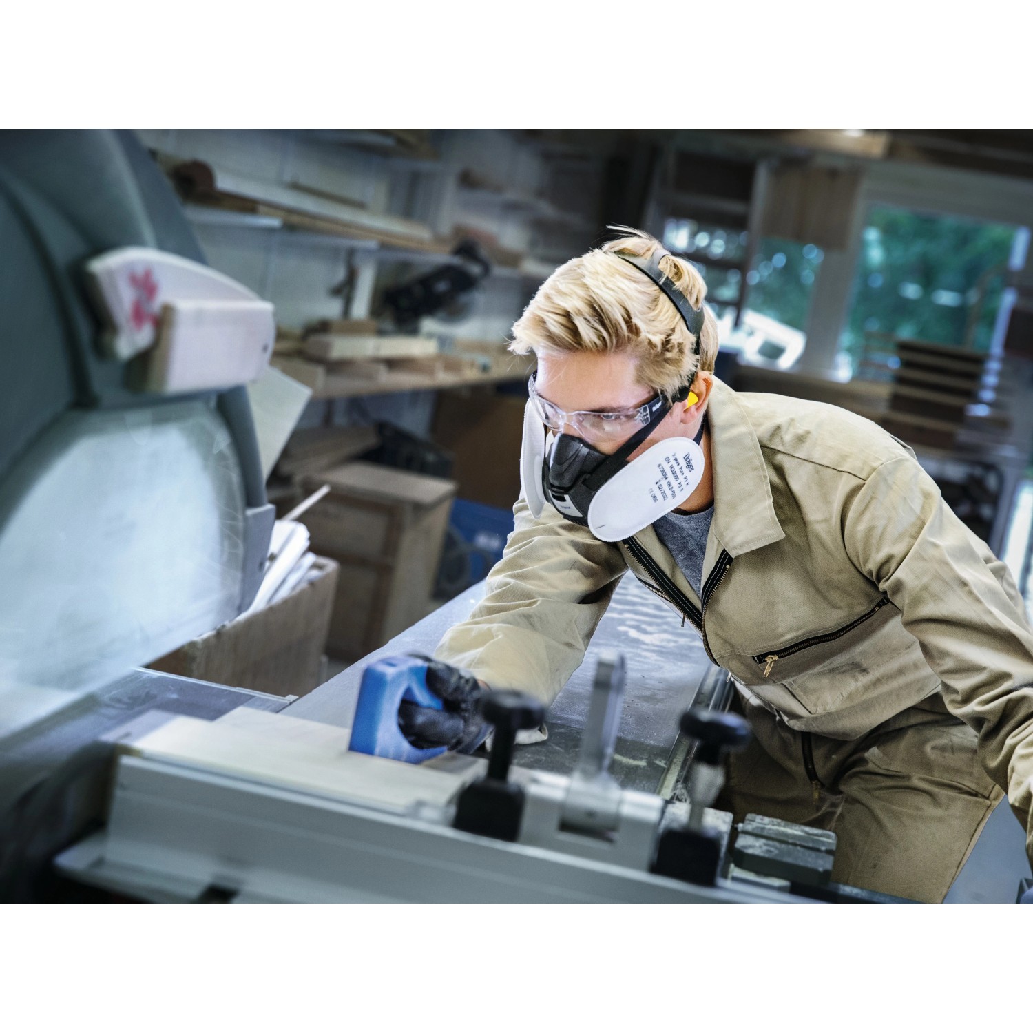 Handwerker mit Dräger Partikelfilter P3 R und Schutzbrille beim Holzzuschnitt.