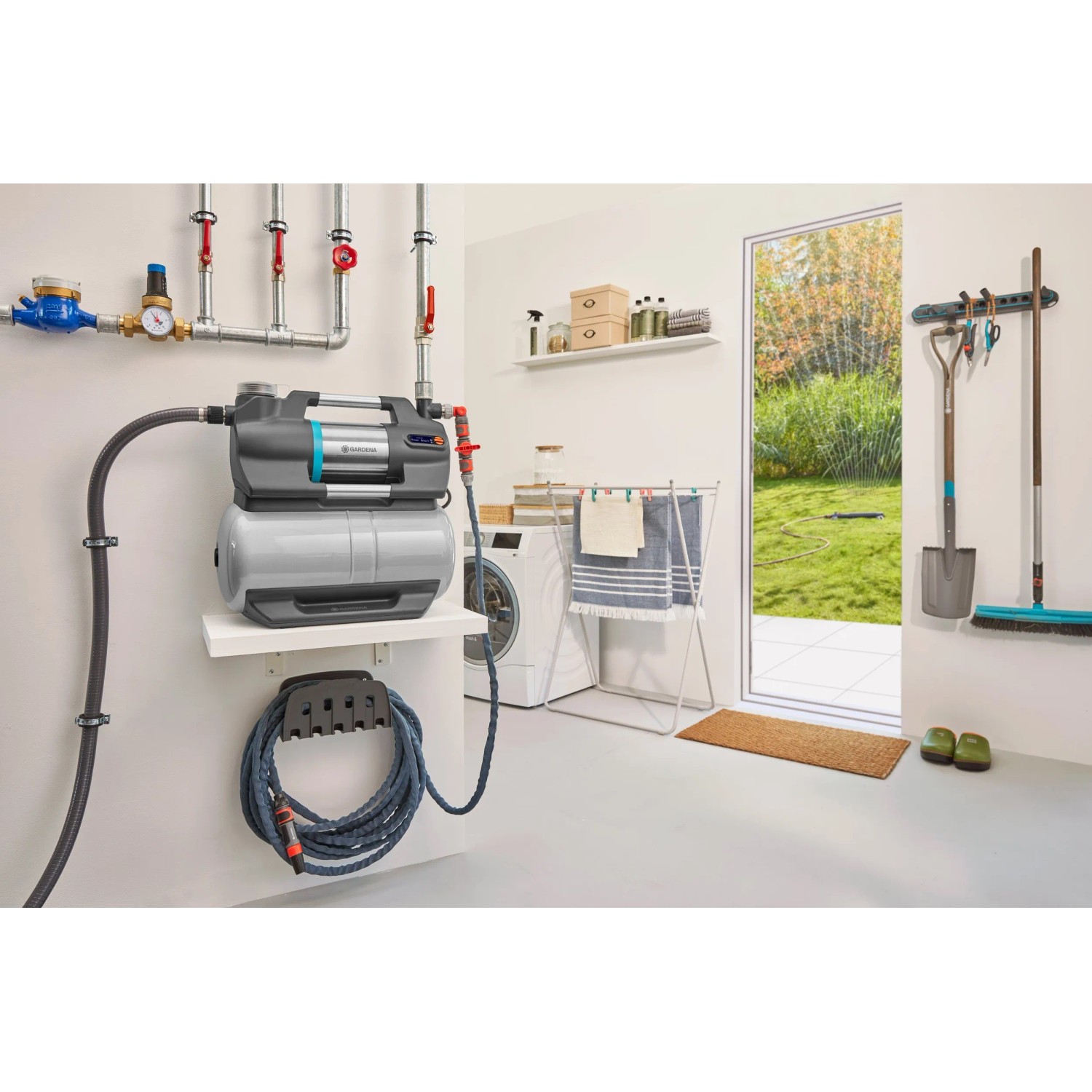 Gardena Hauswasserwerk 5600 SilentComfort mit grauem Tank und Schlauch an weißer Wand im Hauswirtschaftsraum.