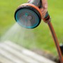 Gardena Comfort Multibrause in Aktion: Hand hält Gartenspritze mit Wasserstrahl.