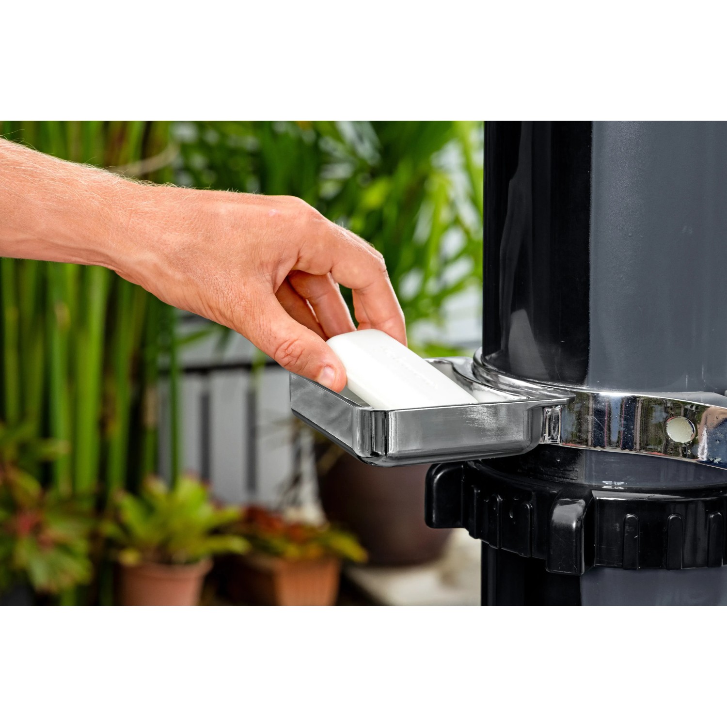 Detailaufnahme: Hand legt Seife in die Ablage der Bestway Solarflow Gartendusche.