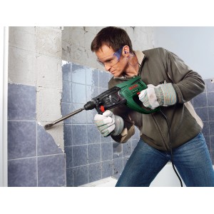 Mann arbeitet mit Bosch Bohrhammer PBH 2800 RE an Fliesenwand. Der Bohrhammer ist grün und schwarz.