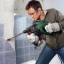 Mann arbeitet mit Bosch Bohrhammer PBH 2800 RE an Fliesenwand. Der Bohrhammer ist grün und schwarz.