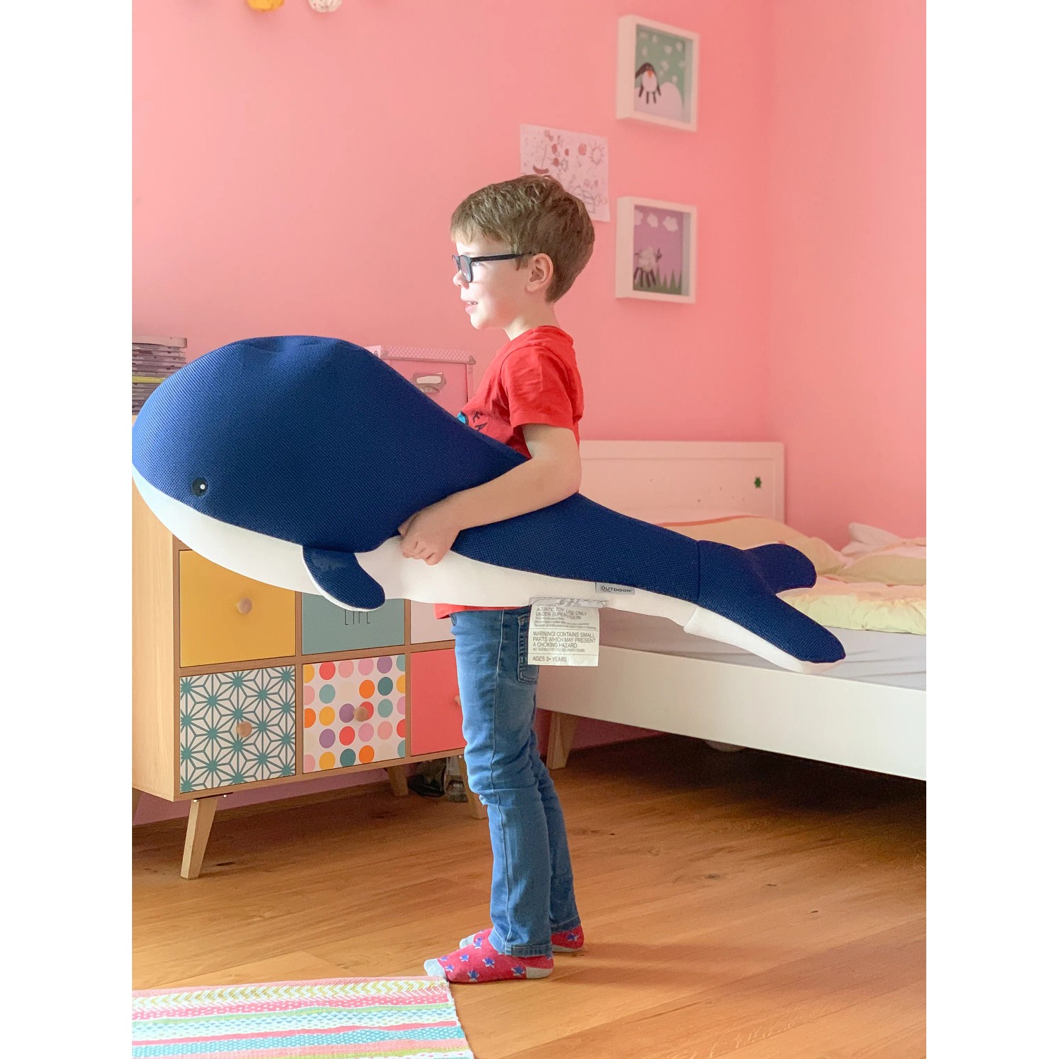 Junge hält blauen Westmann Pool Buddy Wal. Kuscheltier, Sitzsack und Schwimmtier.